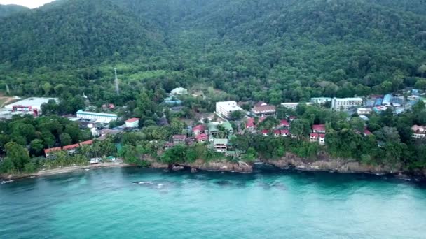 Dawn op Chang eiland. Turkoois helder water met golven reflecteert het milieu. Lichte wolken met roze kleur, groene heuvels, palmbomen. Een scherpe druppel in het water. Schieten van een drone. Thailand. — Stockvideo