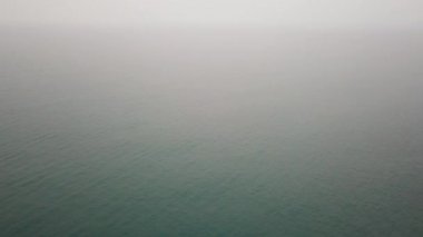 Kamboçya 'daki yangın nedeniyle, ağır duman denizde görüş açısını kapatıyor. Hiçbir şey görünmüyor, sadece karanlık bir deniz ve beyaz bir sis var. Denize doğru uç, ufuk. Bir İHA 'dan ateş etmek. Korkuyorum..