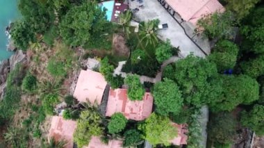 Yeşil Chang adası Kamboçya 'daki bir yangından dolayı dumanla kaplandı. Yeşil ağaçlar, palmiye ağaçları ve tepeler sis bulutlarıyla kaplıdır. Oteller denizin önündeki bir uçurumun üzerinde duruyor. Turkuaz su.