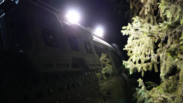 Bir off road aracının arka kapağını kapatın. İçinde gece çevredeki ormanı aydınlatan ışıklarla dolu bir depo var. Bu da engebeli ve maceracı bir atmosfer yaratıyor.