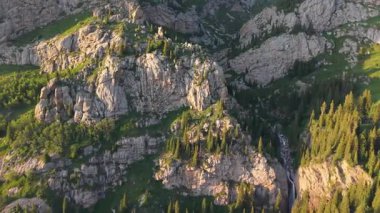 Güneş ışığı giderek kayalık dağ yamaçlarını aydınlatıyor, kozalaklı ormanı ve çağlayan şelaleyi ortaya çıkarıyor el değmemiş vahşi doğada yuva yapmış.