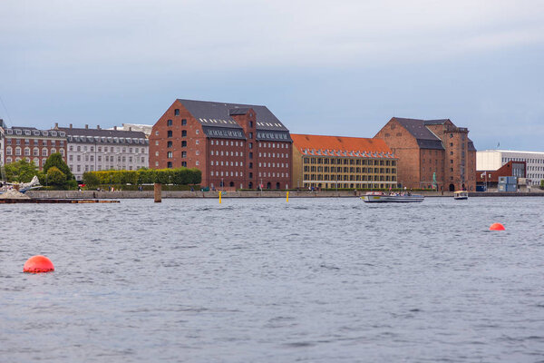 Copenhagen, Denmark- 29 August 2014: View of the Copenhagen old city from the barge flowing down the channel. Old red brick buildings.