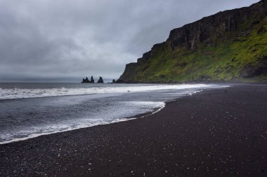 Vik ve Myrdal 'daki siyah, volkanik plaj manzarası. Arka planda Reynisdrangar kaya oluşumu. İzlanda.