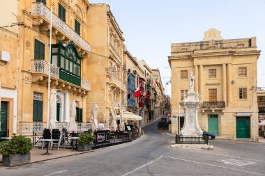 Birgu, Malta - 26 Haziran 2021: Eski kasabanın renkli balkonları ve geleneksel kapılarıyla sessiz dar bir taş sokak.