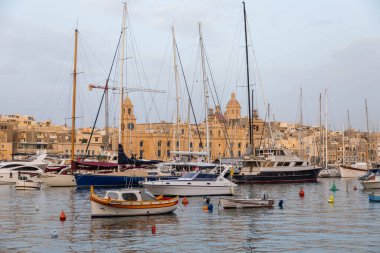 Birgu, Malta - 26 Haziran 2021: Limanda demirlemiş tekne ve yatlar, sudaki tarihi binaların yansıması..