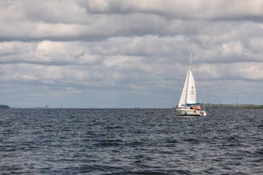 Szczecin, Polonya, 01 Ağustos 2021: Szczecin Gölünde bulutlu bir gökyüzünün altında görünür bir ruhsata sahip bir yelkenli..