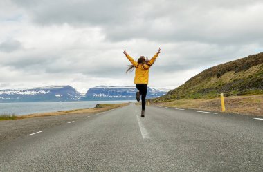 İzlanda'daki bir yolda bir sarı yağmurluk kız çalıştıran