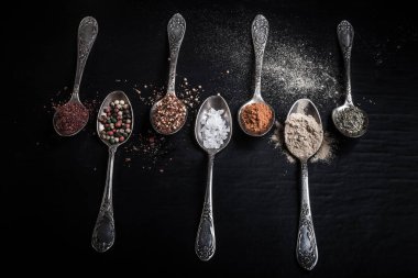 Siyah bir zemin üzerine baharat farklı tipteki eski metal kaşık. Tonda.