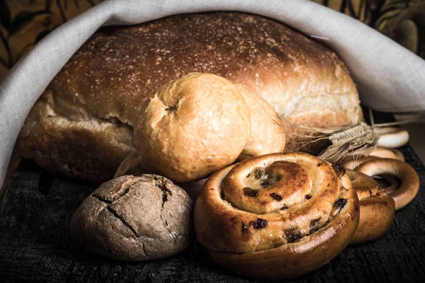 Eski ahşap masa üzerinde taze ekmek ve buğday sivri farklı türleri. Sığ derinlik-in tarla. Seçici odak. Tonda.