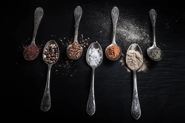 Siyah bir zemin üzerine baharat farklı tipteki eski metal kaşık. Tonda.