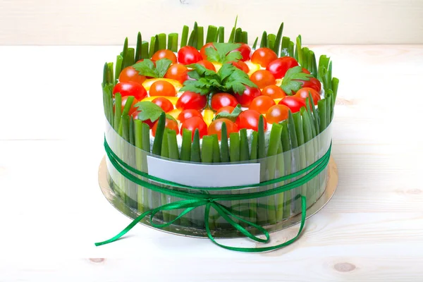 Non-sweet holiday cake with red fish, green onion, cherry tomatoes, cream cheese and parsley on light wooden background.