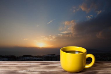 Kahve ya da çay ahşap tablo karşısında arka plan için Akdeniz üzerinde güzel günbatımı üzerinde sarı Kupası'nda. Türkiye'de sonbahar. Alanya. Doğal arka plan. Gökdelenin çatı görüntülemek.