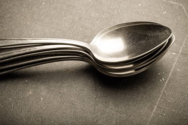 Çok fazla siyah bir zemin üzerine metal çatal bıçak takımı. Seçici odak. Sığ derinlik-in tarla. Tonda.