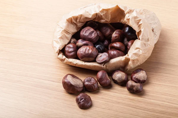 Kastanien Einer Papiertüte Auf Einem Hellen Holztisch — Stockfoto