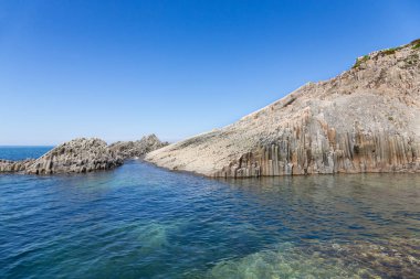 Cape Stolbchaty. Cape Kunashir Adası batı kıyısında. Mendeleyev volkanın bazaltik lavaş katmanların oluşur.