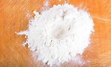 Beyaz buğday unu yığını bir eski yıpranmış kesme tahtası üzerinde dağınık olduğunu.