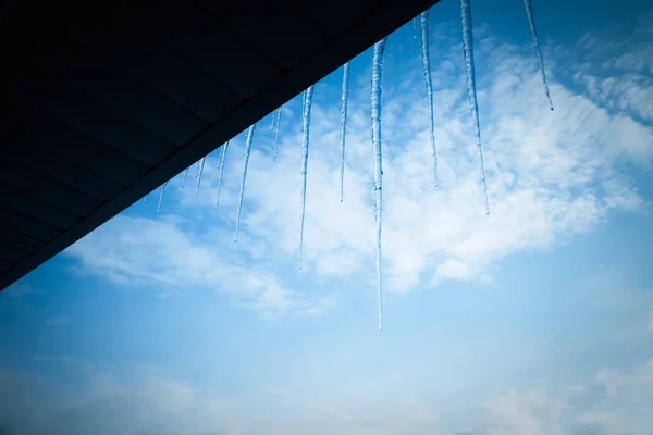 青空背景の屋根の上に透明なつらら トーン — ストック写真