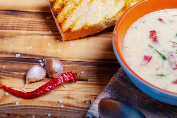Würzige Suppe mit saurer Sahne, Brot und Gewürzen auf verbranntem Holz — Stockfoto