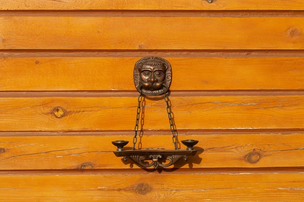 Figura decorativa de hierro fundido en una pared de madera de una casa rural —  Fotos de Stock