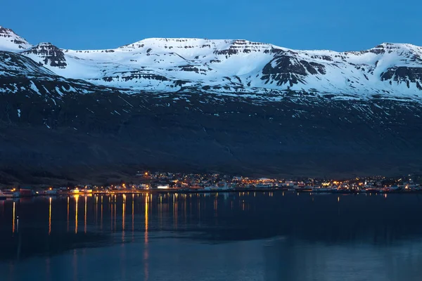 Vista noturna para a pequena cidade e montanhas nevadas no fiorde de — Fotografia de Stock
