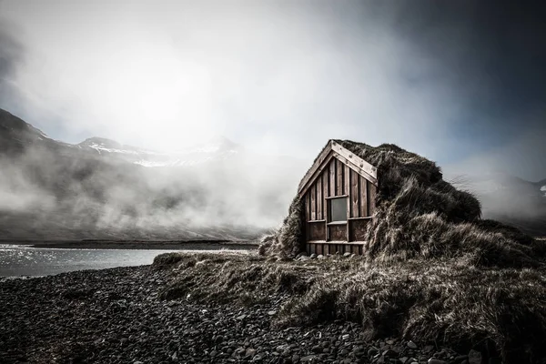 Pequena casa de madeira com telhado de grama no fiorde Islândia. Tonificado — Fotografia de Stock