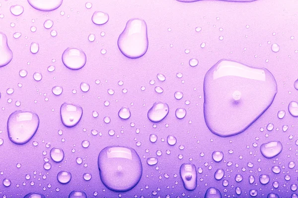 Gocce d'acqua su uno sfondo a colori. Concentrazione selettiva. Viola. T — Foto Stock