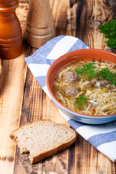 Hausgemachte Suppe mit Nudeln und Frikadellen auf einem Holztisch. trad — Stockfoto