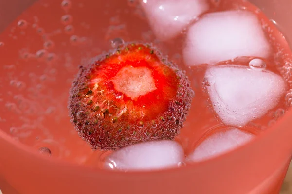 Vidro com água espumante e frash morangos brilhantes em um su — Fotografia de Stock