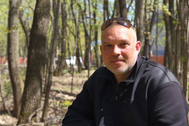 Bir adam 35-40 yaşında oturan bir ormanda bir şehir parkı portresi.