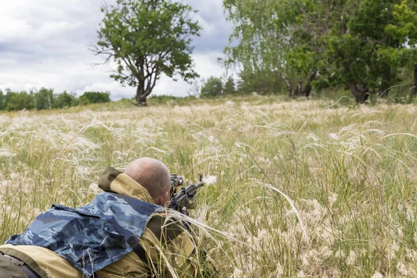 Hunting season. A 35-40-year-old man hunts and targets a firearm in the grass.