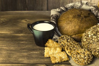 Gıda. Ülke kahvaltı. Taze ekmek ürün yelpazesine bir ekmek, bisküvi ve ahşap masa arka plan üzerinde süt ile bir kupa pişmiş