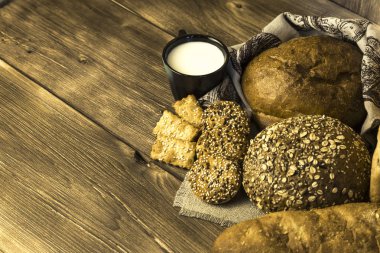 Gıda. Kırsal kahvaltı. Taze ekmek ürün yelpazesine bir ekmek, bisküvi ve ahşap masa arka plan üzerinde süt ile bir kupa pişmiş