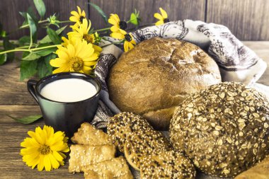 Gıda. Rustik natürmort. Taze ekmek ürün yelpazesine bir ekmek, bisküvi ve ahşap masa arka plan üzerinde süt ile bir kupa pişmiş