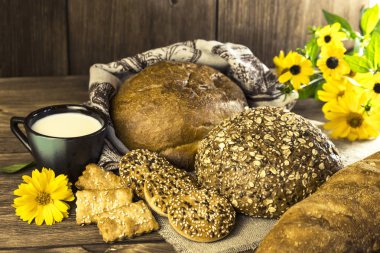 Gıda. Rustik natürmort. Taze ekmek ürün yelpazesine bir ekmek, bisküvi ve ahşap masa arka plan üzerinde süt ile bir kupa pişmiş