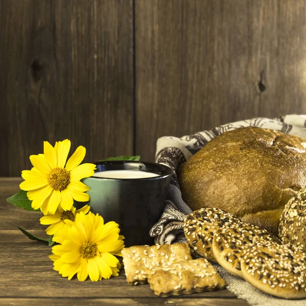 Gıda. Rustik natürmort. Taze ekmek ürün yelpazesine bir ekmek, bisküvi ve ahşap masa arka plan üzerinde süt ile bir kupa pişmiş