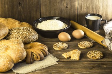 Gıda. Rustik natürmort. Bir ekmek, bisküvi, tavuk yumurtası ve süzme peynir bir ahşap masa doku arka plan üzerinde taze ekmek