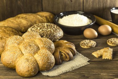 Gıda. Ekmek pişirme. Bir ekmek, bisküvi, tavuk yumurta ve un bir ahşap masa doku arka plan üzerinde taze ekmek