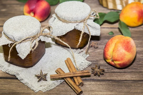 Cibo. Frutta in scatola fatta in casa in lattine. Marmellata di pesche alla frutta e pesche fresche mature sullo sfondo di un tavolo di legno in stile rurale — Foto Stock