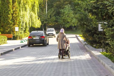 Saratov, Rusya Federasyonu - 10/07/2018: genç kadın anne yürür arabasındaki bebek sonbahar parkta çocuk ile.