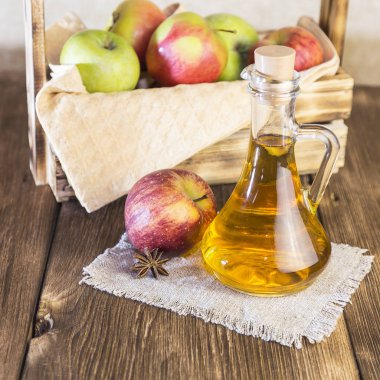 Kırmızı ve yeşil elma tarımsal bir ürün işleme. Ev yapımı hazırlıkları, sağlıklı diyet vejetaryen yemekleri. Baharatlı elma elma şarabı sirke, meyve suyu, elma şarabı olgun meyve kutusunun yanındaki cam sürahi