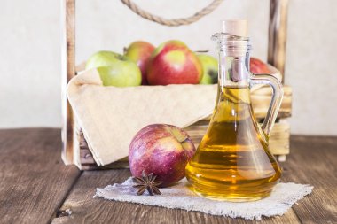 Kırmızı ve yeşil elma tarımsal bir ürün işleme. Ev yapımı hazırlıkları, sağlıklı diyet vejetaryen yemekleri. Baharatlı elma elma şarabı sirke, meyve suyu, elma şarabı olgun meyve kutusunun yanındaki cam sürahi