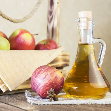 Kırmızı ve yeşil elma tarımsal bir ürün işleme. Ev yapımı hazırlıkları, sağlıklı diyet vejetaryen yemekleri. Baharatlı elma elma şarabı sirke, meyve suyu, elma şarabı olgun meyve kutusunun yanındaki cam sürahi