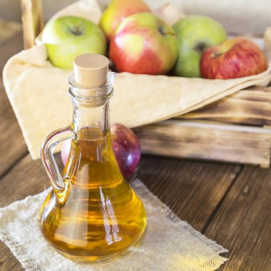 Kırmızı ve yeşil elma tarımsal bir ürün işleme. Ev yapımı hazırlıkları, sağlıklı diyet vejetaryen yemekleri. Baharatlı elma elma şarabı sirke, meyve suyu, elma şarabı olgun meyve kutusunun yanındaki cam sürahi