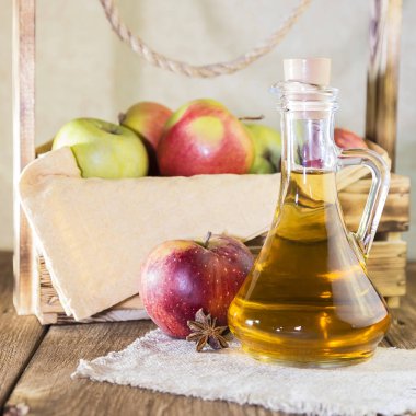 Kırmızı ve yeşil elma tarımsal bir ürün işleme. Ev yapımı hazırlıkları, sağlıklı diyet vejetaryen yemekleri. Baharatlı elma elma şarabı sirke, meyve suyu, elma şarabı olgun meyve kutusunun yanındaki cam sürahi