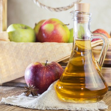 Kırmızı ve yeşil elma tarımsal bir ürün işleme. Ev yapımı hazırlıkları, sağlıklı diyet vejetaryen yemekleri. Baharatlı elma elma şarabı sirke, meyve suyu, elma şarabı olgun meyve kutusunun yanındaki cam sürahi