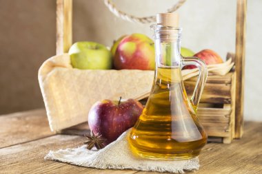 Kırmızı ve yeşil elma tarımsal bir ürün işleme. Ev yapımı hazırlıkları, sağlıklı diyet vejetaryen yemekleri. Baharatlı elma elma şarabı sirke, meyve suyu, elma şarabı olgun meyve kutusunun yanındaki cam sürahi