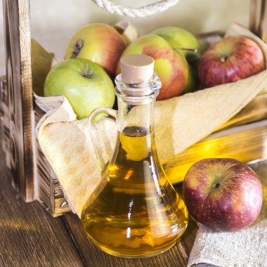 Kırmızı ve yeşil elma tarımsal bir ürün işleme. Evde konserve, sağlıklı diyet vejetaryen yemek. Baharatlı elma elma şarabı sirke, meyve suyu, elma şarabı olgun meyve kutusunun yanındaki cam sürahi