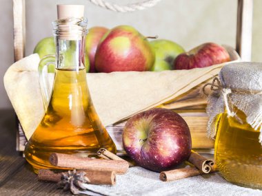 Kırmızı ve yeşil elma tarımsal bir ürün işleme. Evde konserve, sağlıklı diyet vejetaryen yemek. Baharatlı elma elma şarabı sirke, meyve suyu, bir sandık dolusu olgun meyve yanındaki cam sürahi içinde tarçınlı elma şarabı