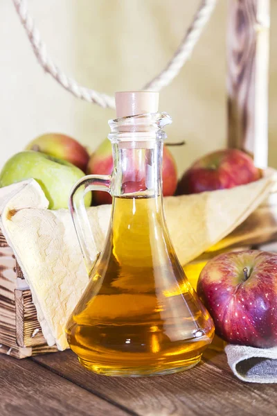 Kırmızı ve yeşil elma tarımsal bir ürün işleme. Evde konserve, sağlıklı diyet vejetaryen yemek. Baharatlı elma elma şarabı sirke, meyve suyu, elma şarabı olgun meyve kutusunun yanındaki cam sürahi
