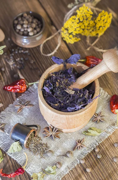 Fragrant torkade helande örter för terapi och kryddig kryddor. På bordet i en mortel är lila basilika, renfana, peppar, chili och kardemumma, i rustik stil. — Stockfoto